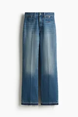 Jeans de tiro alto en denim de algodón rígido, color azul medio con efecto degradado (ombré) que se oscurece hacia el bajo. Corte acampanado (flare) y bajo deshilachado. Presenta bolsillos parche con botón en la parte delantera y trabillas ajustables con botón a los lados de la cintura.