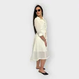 Vestido camisero midi negro con cuello clásico, mangas 3/4 y falda acampanada. Presenta un cinturón de lazo en la cintura y cierre frontal con botones.