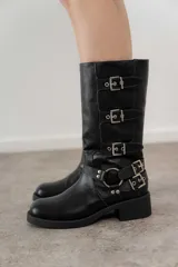 Bota negra de caña media confeccionada en cuero sintético, con hebillas plateadas y taco bajo.