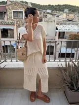 Pollera midi color crudo, de tejido calado con abertura lateral y cintura elastizada con cordón.