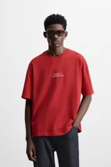 Camiseta roja de corte relajado, cuello redondo y manga corta. Estampado con texto en el frente y la espalda.