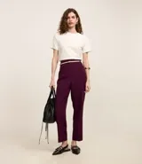 Pantalón de vestir color borgoña, de corte zanahoria, con cinturón fino color rosa pálido y hebilla metálica.