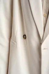 Blazer color crema, de corte oversize, con solapas de muesca, cierre con doble botón y bolsillos laterales con solapa.