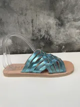 Sandalias chatas con tiras trenzadas de cuero metalizado color celeste.