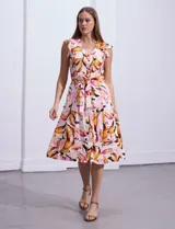Vestido camisero midi estampado con flores en tonos rosa, naranja y marrón sobre fondo blanco. Tiene escote en V, abertura frontal con botones, mangas cortas con volados y lazo de ajuste en la cintura.