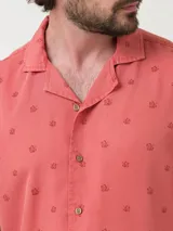 Camisa celeste con estampado de peces negros, de manga corta y corte recto.