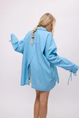 Camisa blanca de lino y algodón, con cuello clásico, cierre frontal con lazos y mangas largas abullonadas con puños ajustables con lazos.