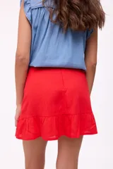 Falda corta de lino color rojo, con diseño de tiro alto y un volado en el ruedo. Posee cierre en la parte posterior.