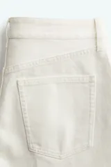 Bermuda blanca de denim rígido de algodón, corte holgado, tiro bajo, cinco bolsillos, raya adelante y atrás, y cierre con botón.