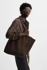 Bolso tipo shopper color marrón claro, fabricado en piel serraje. Cuenta con dos asas de mano y un bolsillo interior con cierre de cremallera.
