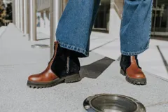 Botas de cuero marrón con paneles de corderito en color beige en la caña. Cuentan con una suela de goma tipo track en tono tostado y cierre de cremallera lateral.