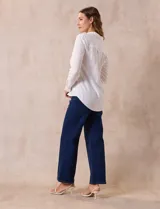 Camisa blanca de manga larga con cuello con solapa y abertura central con botones. Tiene dos bolsillos delanteros aplicados.