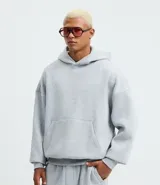 Buzo con capucha y bolsillo canguro delantero, color gris melange, de corte recto y holgado.