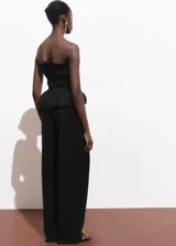 Pantalón negro de tiro medio y corte recto, confeccionado en mezcla de algodón y poliamida. Presenta trabillas, dos bolsillos laterales y cierre oculto de botón, gancho y cremallera.