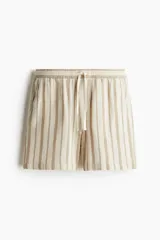 Short de algodón a rayas verticales color beige y marrón claro, con cintura elástica ajustable con cordón, bolsillos laterales y bolsillo trasero.