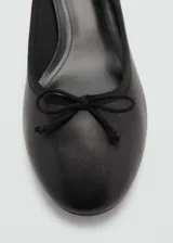 Zapato de tacón color beige con punta redonda y detalle de lazo.