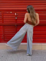 Pantalón de jean celeste de tiro medio con pierna extra ancha y caída fluida, con bolsillos delanteros y traseros, y cierre frontal con cremallera y botón metálico.