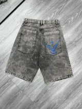 Bermuda de jean de corte ancho (baggy), color gris oscuro con efecto lavado ácido (acid wash). Presenta un bordado azul eléctrico con diseño abstracto/geométrico en el bolsillo trasero derecho.
