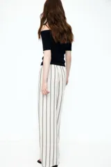 Pantalón de corte holgado en tejido liviano de mezcla de lino. Modelo de tiro alto con cintura elástica y cordón para ajustar fino, bolsillos laterales discretos y piernas rectas. Diseño a rayas verticales en blanco y negro.