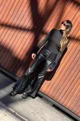 Pantalón Oxford negro de cuero sintético con cierre frontal y aberturas laterales con pasamanería plateada.