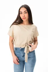 Remera beige de algodón y elastano, con escote redondo y corte a la cintura con lazo lateral.