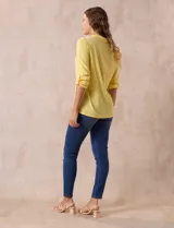 Blusa blanca de poliéster y rayón con escote en V bordado y mangas tres cuartos regulables con presilla y botón.