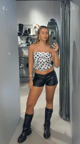 Top strapless blanco con estampado de lunares negros y detalle de nudo con argolla dorada en el centro.