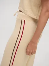 Pantalón negro de algodón, corte holgado y pierna ancha con pretina elástica. Presenta rayas blancas y celestes a los costados.