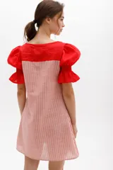 Vestido corto con cuerpo a rayas verticales en tonos beige y blanco, mangas cortas abullonadas y canesú superior en color negro.