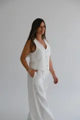 Pantalón palazzo color blanco hueso, de tiro alto y corte holgado. Confeccionado en lino.
