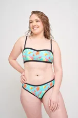 Top de bikini con escote corazón y estampado floral en tonos rosa, naranja, amarillo y blanco. Tiene breteles finos regulables y contorno inferior en color celeste.