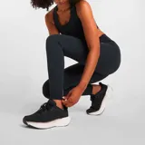 Calza larga de training New Balance modelo Harmony High Rise, color negro, con cintura alta y logo reflectivo en la pierna.