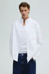 Camisa blanca de algodón Oxford con cuello americano, tapeta clásica, bolsillo superior abierto y canesú en la espalda. Mangas largas con puños abotonados y bajo levemente redondeado. Corte estándar.