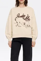 Sudadera color crema de algodón con cuello redondo y mangas largas. Estampado frontal con el logo de la marca y un dibujo de un perro.