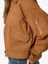 Campera bomber color marrón de poliéster con cuello camisero, mangas largas, cierre de cremallera al frente, bolsillos delanteros y ruedo elastizado.