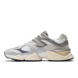 Championes New Balance U9060, color gris claro con detalles en gris oscuro y blanco. Capellada de gamuza y malla, con logo "N" en los laterales y suela gruesa con tecnología ABZORB y SBS.