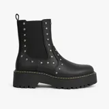 Bota Chelsea color crema con plataforma track negra y elásticos laterales con tachas plateadas.
