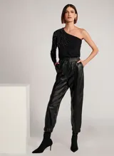 Pantalón jogger de cuero negro con cinturilla elástica y cordones, bolsillos delanteros y traseros, y bajos ajustados.