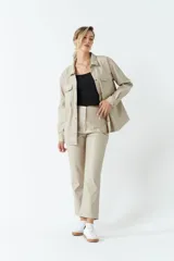 Sobrecamisa color beige de efecto cuero, con cuello clásico, cierre frontal con botones a tono, mangas largas con puños abotonados, dos bolsillos con solapa en el pecho y corte recto.