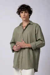 Camisa verde oliva de lino, de corte holgado, con cuello clásico y mangas largas con puños abotonados.
