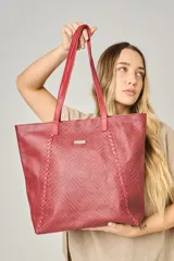 Bolso grande tipo tote color rojo ladrillo, con diseño tejido y asas de cuero. Cuenta con cierre superior, forro interior con bolsillo para celular y bolsillo con cierre, y bolsillo trasero con cierre.