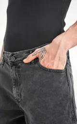 Bermuda de denim rígido, color negro lavado (acid wash), de cinco bolsillos y corte regular, con ruedo desflecado.