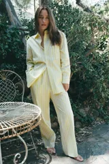 Pantalón tipo pijamero con tiro alto y cintura elástica, confeccionado en hilatura con algodón y lino. Presenta un estampado a rayas verticales en color amarillo y blanco, y detalle de botones decorativos en el delantero.