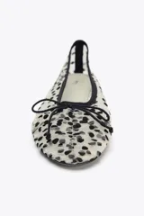Zapato tipo bailarina de malla color blanco con estampado de lunares negros, detalle de lazo en la puntera, tirador trasero y suela plana.