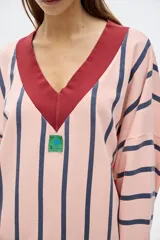 Buzo de algodón lavado a rayas rosas y azul marino, de fit oversized, manga larga y hombros caídos. Cuello en V, terminaciones a contratono y parche en el frente.