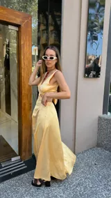 Vestido largo color durazno con escote pronunciado en V y aberturas laterales en la cintura. Presenta un drapeado frontal y falda con tajo lateral.