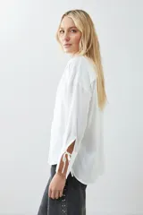 Camisa color crudo de tela satinada con lazos en el escote y mangas largas.