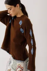 Sweater color gris claro con cuello redondo, mangas largas acampanadas y aberturas circulares en hombros y mangas con detalles de tela blanca.