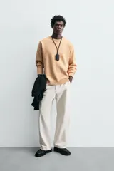 Sweater color arena con textura jaspeada, de corte recto, cuello redondo y mangas largas con terminaciones acanaladas.