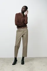 Pantalón de vestir color beige, de tiro alto y corte recto. Incluye cinturón marrón con hebilla metálica. Presenta bolsillos laterales y falsos bolsillos traseros de doble vivo. Cierre frontal con cremallera, botón interior y gancho oculto.